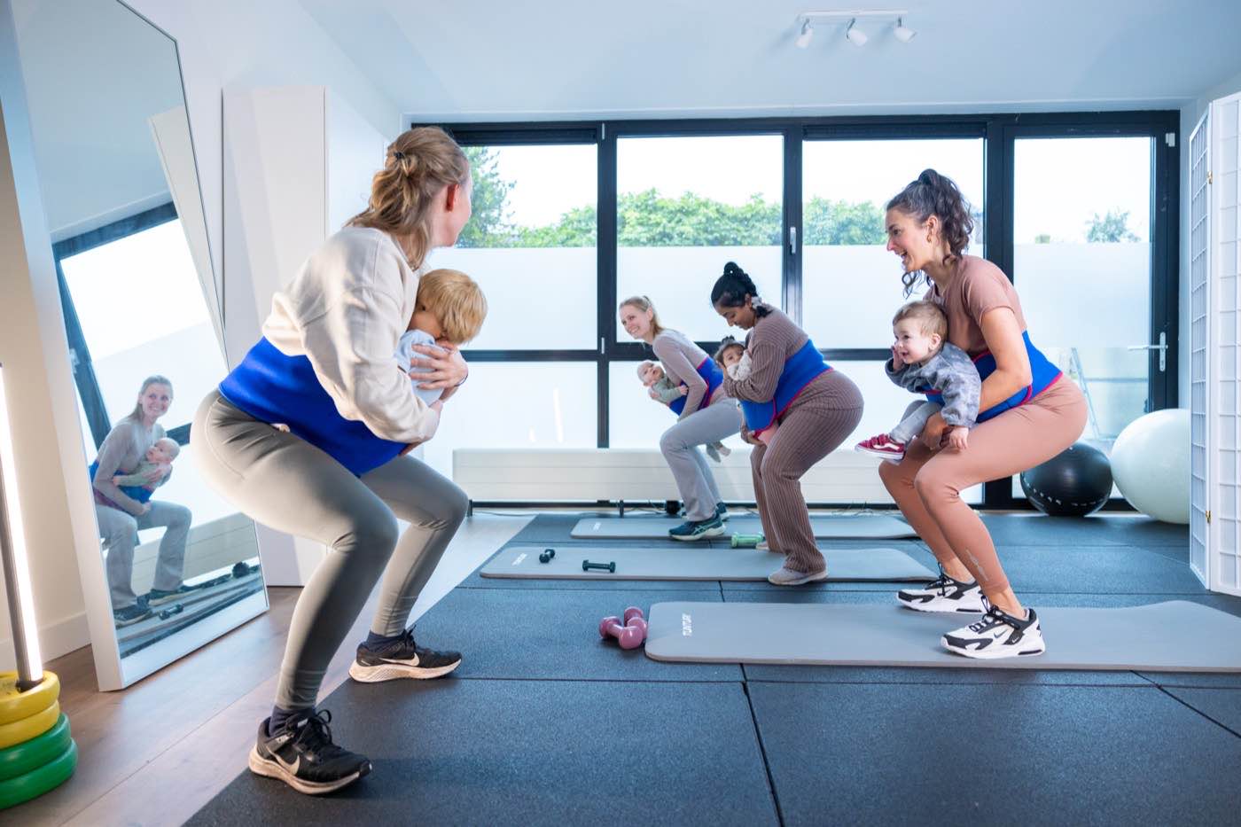 Moeders trainen samen met hun baby's in een lichte trainingsruimte